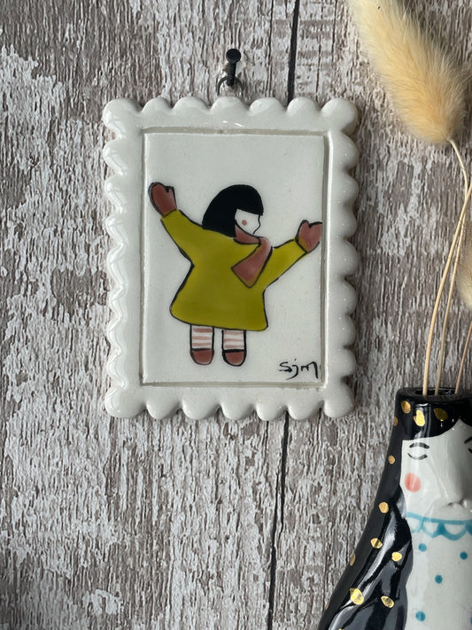 Mini Masterpiece “Nora” Hand-Painted Ceramic Girl in Yellow Coat with Arms Out