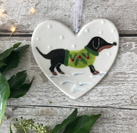 Hand Painted Ceramic Heart Christmas Decoration - Black & Tan Sausage Dog/Dachshund Wearing a Festive Jumper sitting in the snow